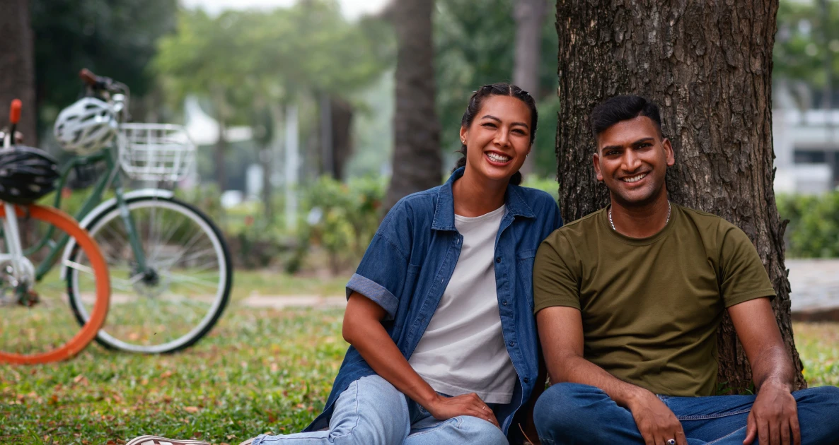 Couple relaxing under a tree with a bicycle nearby.