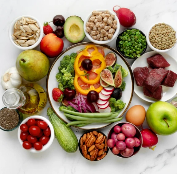 Circle of fruits, vegetables, nuts, and proteins around salad bowl