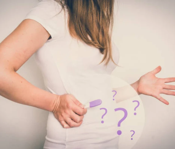 Woman hides pregnancy test, surrounded by question marks.
