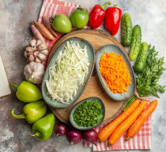 Fresh vegetables and herbs on wooden board with bowls and produce