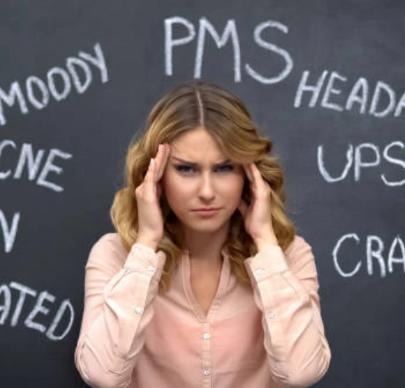 Woman holds her head, surrounded by PMS-related words.