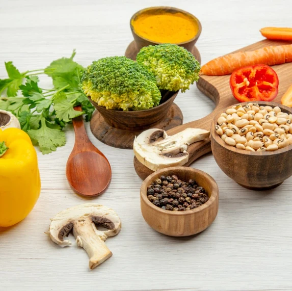 Vegetables, spices, and sauce on wooden surface