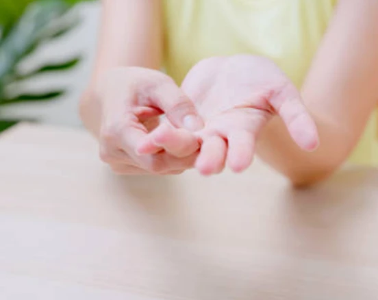 Person massages palm on a wooden table in a calm setting.
