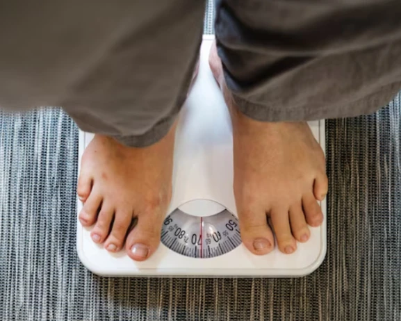 Feet on a weighing scale showing around 60 kg.