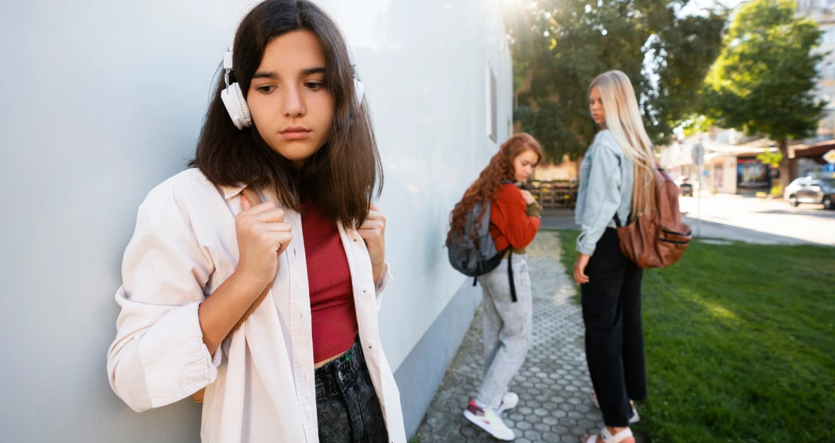 Girl with headphones watching others walk away.