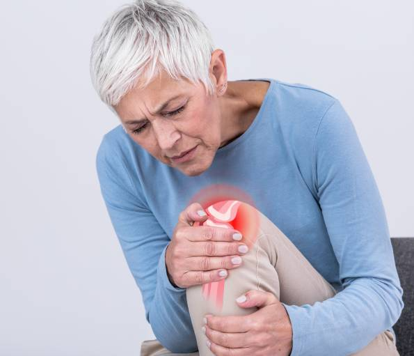 Elderly woman holding knee, pain highlighted.