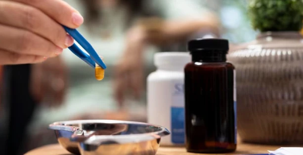 Hand placing capsule with tweezers in dish