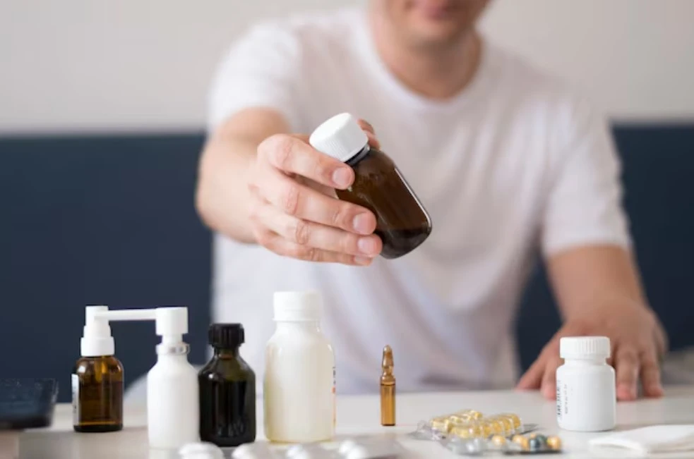 Person reaching for medicine bottle among medications.