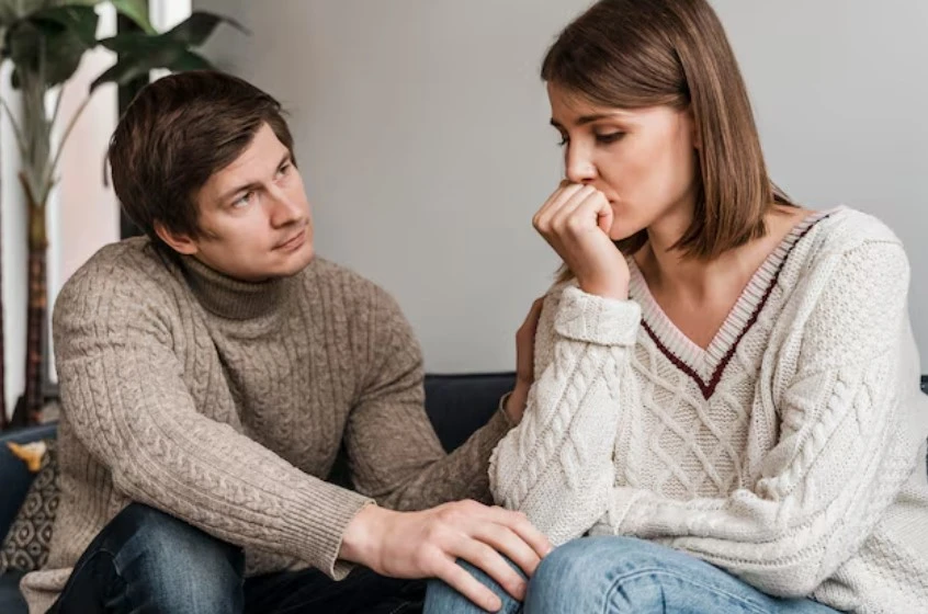 Man comforting thoughtful woman on sofa.