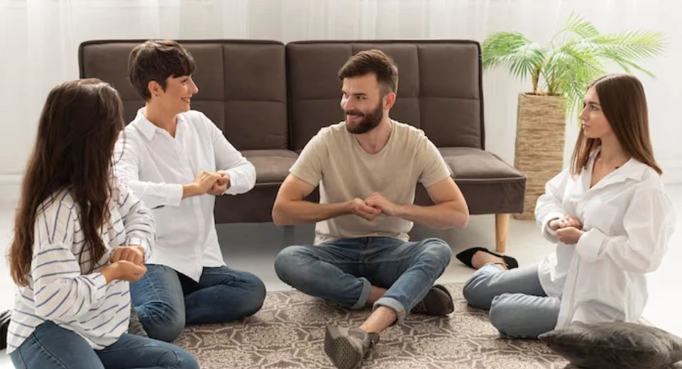 Four people sit cross-legged, smiling and chatting.
