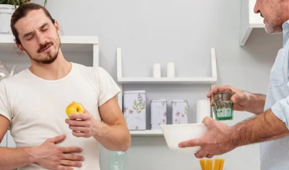 Man with stomach pain holding apple, offered help.