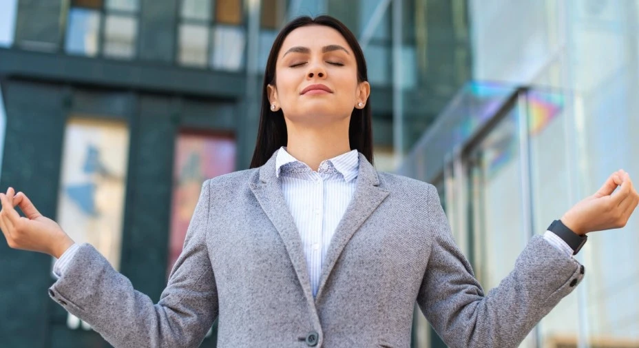 Confident woman meditating outside modern building.