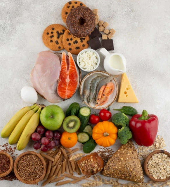 Balanced diet food pyramid arrangement with grains, fruits, vegetables, meat, dairy, and sweets