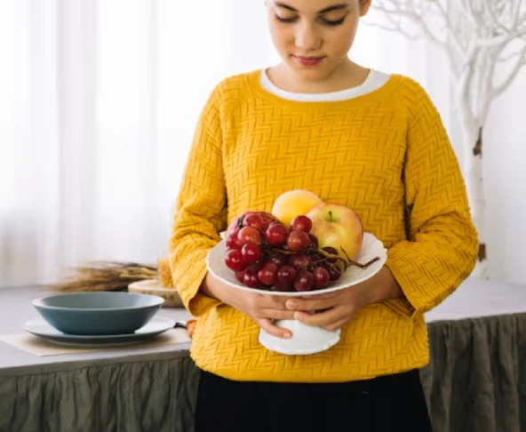 Person holding bowl of fruit in a domestic setting