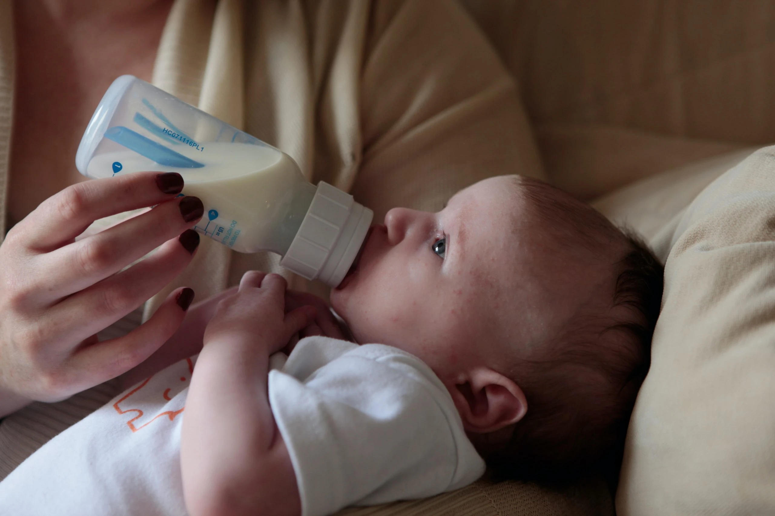 Baby on couch being bottle-fed.