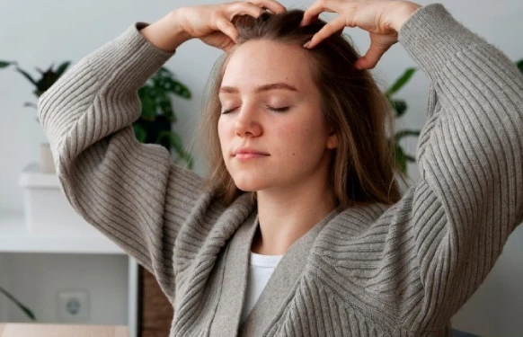 Woman meditating and massaging scalp indoors.