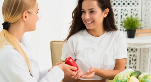 Two women with vegetables, dietitian holding bell pepper