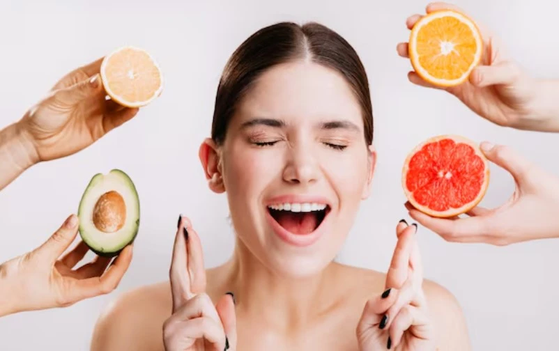 Joyful woman surrounded by fruits with crossed fingers for hope