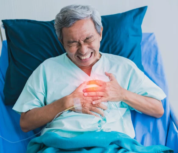 Elderly man in hospital bed clutching chest in pain
